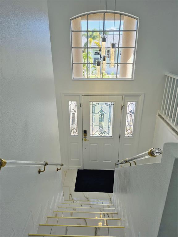 A staircase with clear railings leads down to a front entryway with a decorative door — 5451 TROPIC DRIVE, NEW PORT RICHEY, FL