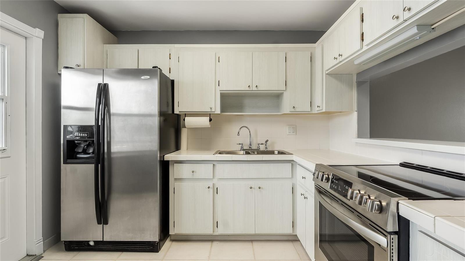 A kitchen features white cabinets, stainless steel appliances, a tiled countertop, and gray walls — 2309 Park Lane # 202, Hollywood FL 33021, HOLLYWOOD, FL