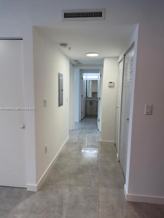 A hallway with light gray tile flooring leads toward a bathroom with wood-toned cabinets — 14752 NE 6th Ave # 305, Miami FL 33161, MIAMI, FL