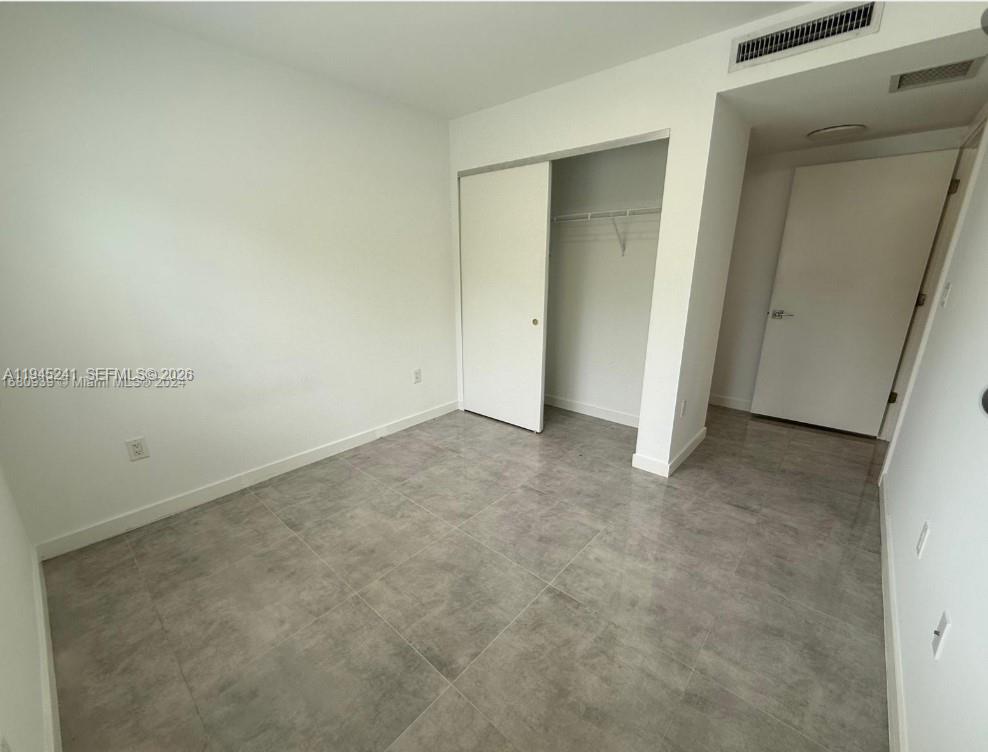 An empty room features white walls, a sliding closet door, and gray tiled flooring — 14752 NE 6th Ave # 305, Miami FL 33161, MIAMI, FL