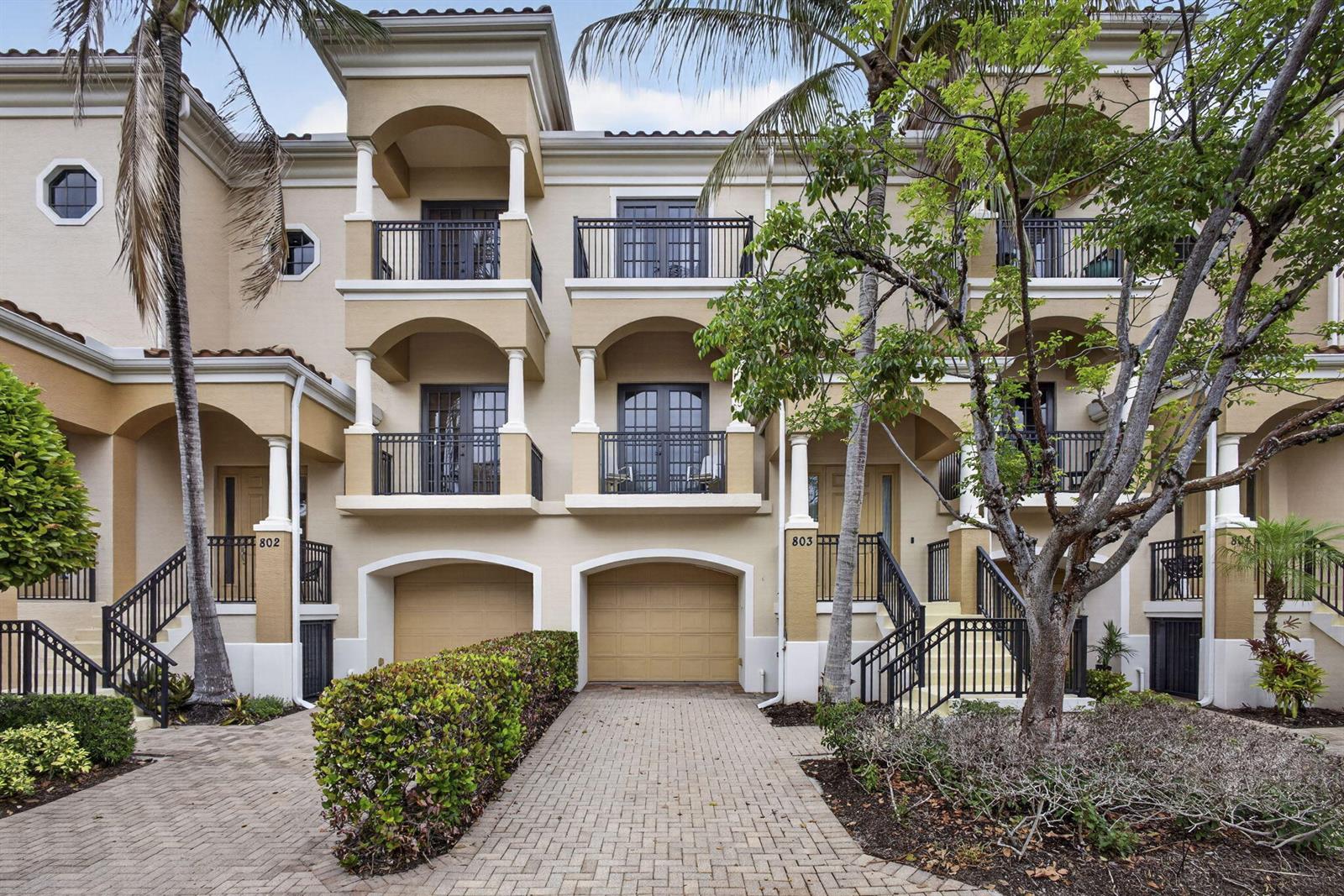 A three-story townhouse exterior features beige stucco walls, arched balconies, and a paved driveway — 803 Del Sol Circle, Tequesta FL 33469, TEQUESTA, FL