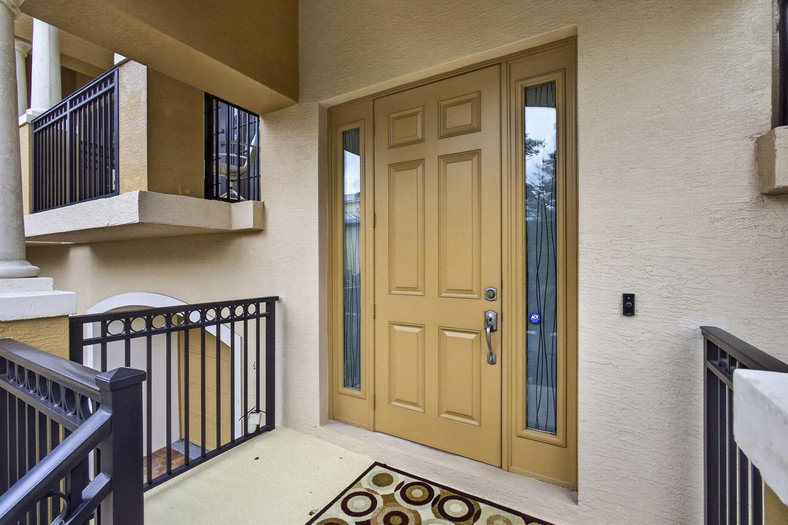 A tan front door with side windows and a metal railing on a covered porch — 803 Del Sol Circle, Tequesta FL 33469, TEQUESTA, FL