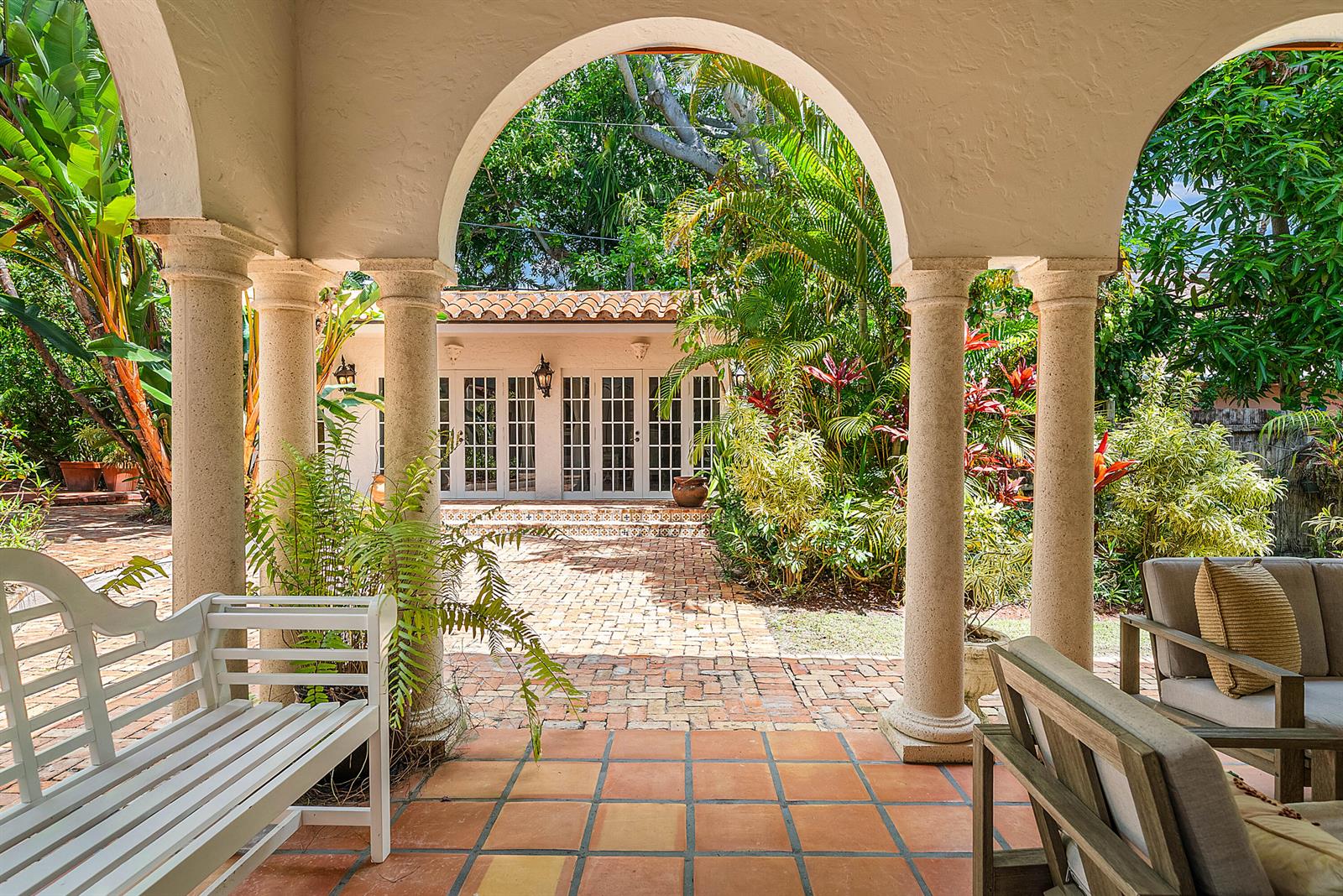 A covered patio with arched columns overlooks a brick courtyard and a small garden house — 255 Cordova Road, West Palm Beach FL 33401, WEST PALM BEACH, FL