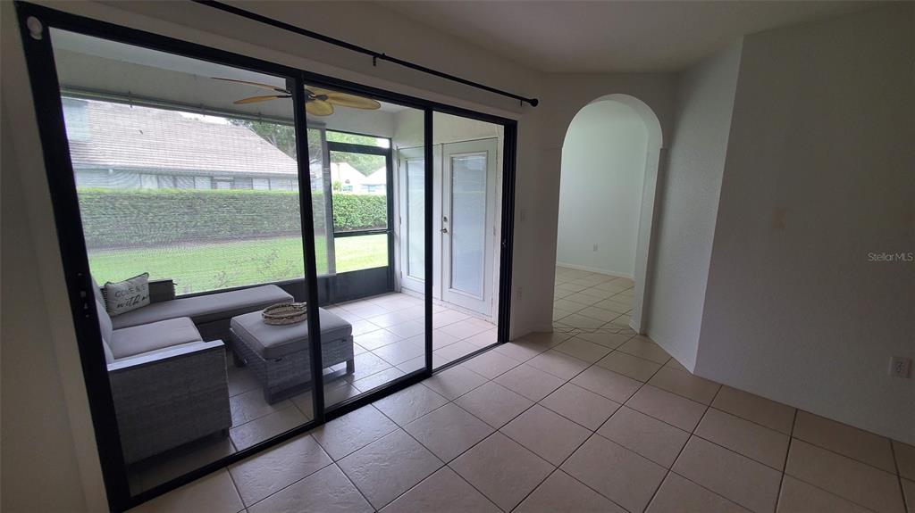 A tiled room features a large sliding glass door opening onto a screened-in patio — 4176 BRENTWOOD PARK CIRCLE, TAMPA, FL