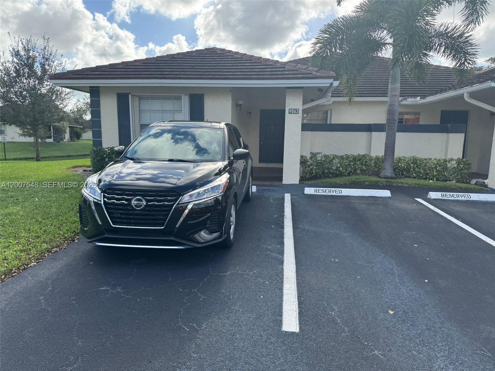 A black Nissan SUV is parked in front of a single-story house with a tiled roof — 9863 Three Lakes Cir, Boca Raton FL 33428, BOCA RATON, FL
