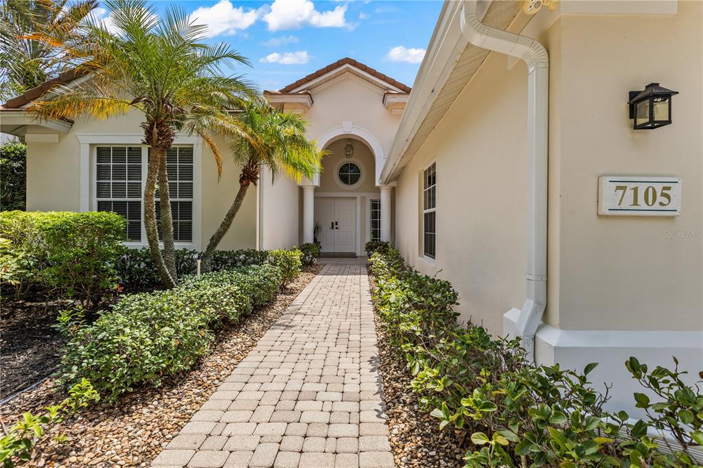 A living room features a wood-slat accent wall, built-in bookshelves, and glass doors to a patio — 7105 VICTORIA CIRCLE, BRADENTON, FL