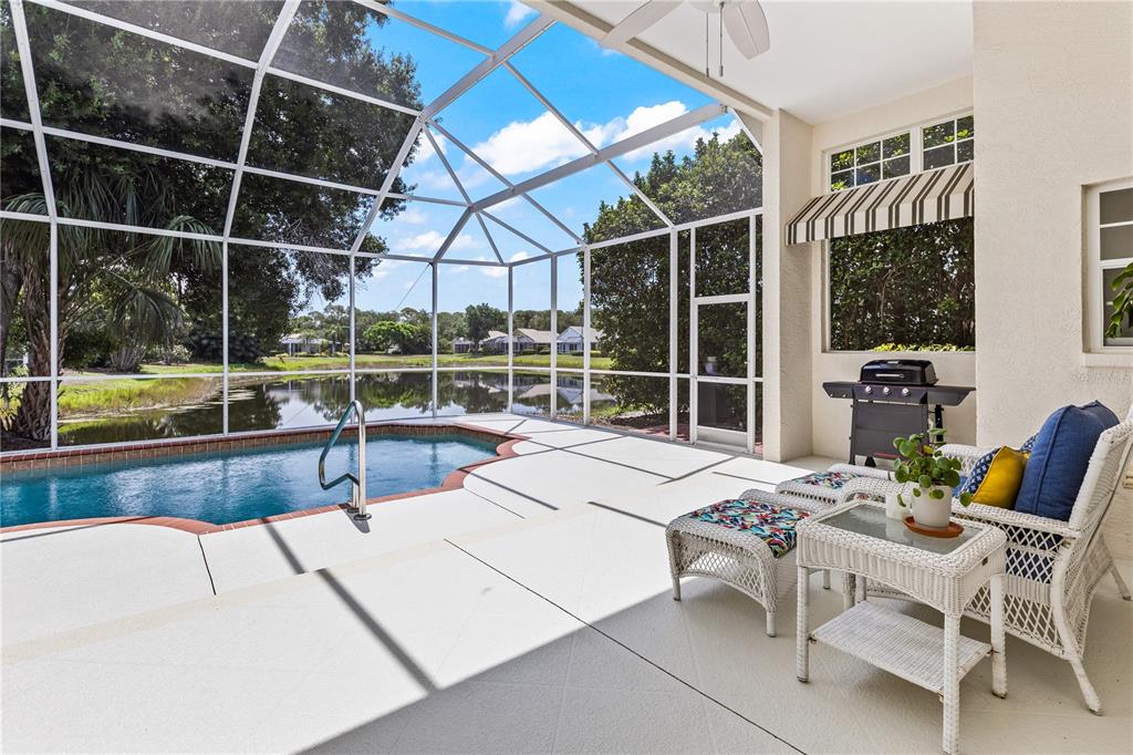 A living room features built-in wooden bookshelves, a gray sofa, and glass doors leading outside — 7105 VICTORIA CIRCLE, BRADENTON, FL