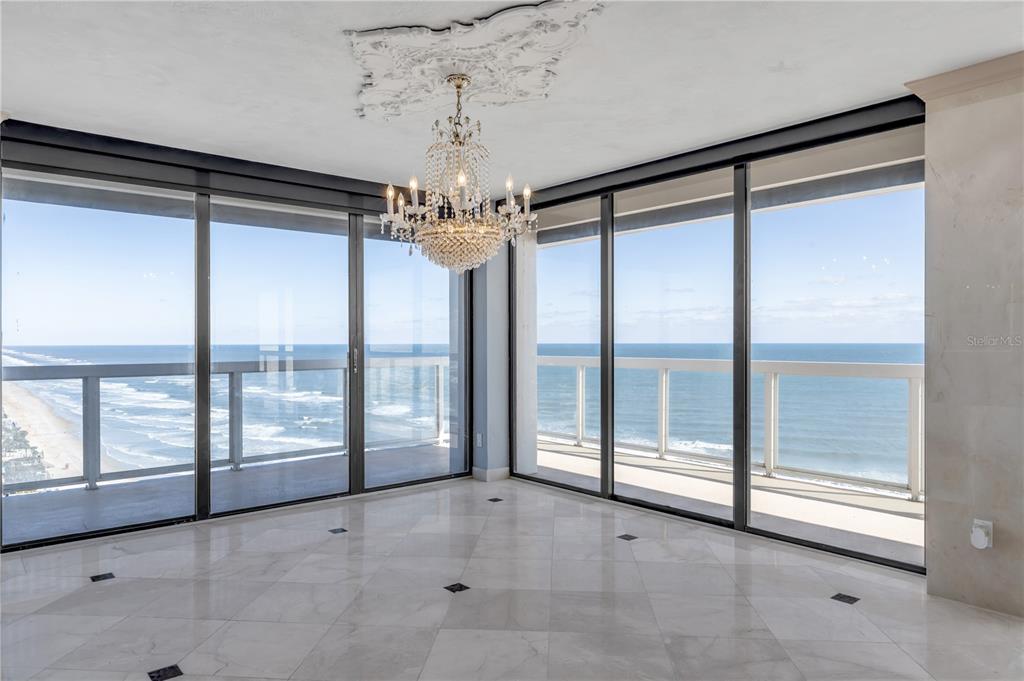 A bright room with marble floors, a crystal chandelier, and floor-to-ceiling windows overlooking the ocean — 3000 N ATLANTIC AVENUE UNIT 18, DAYTONA BEACH, FL