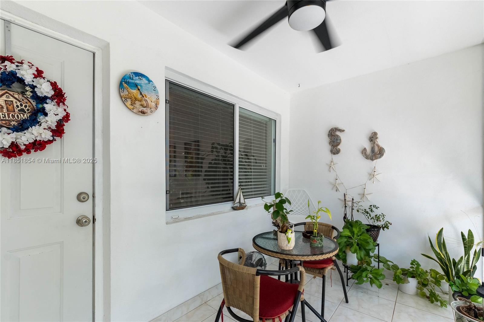 A small covered patio features a bistro set, potted plants, and nautical wall decor — 581 Blue Heron Dr # B, Hallandale Beach FL 33009, HALLANDALE BEACH, FL