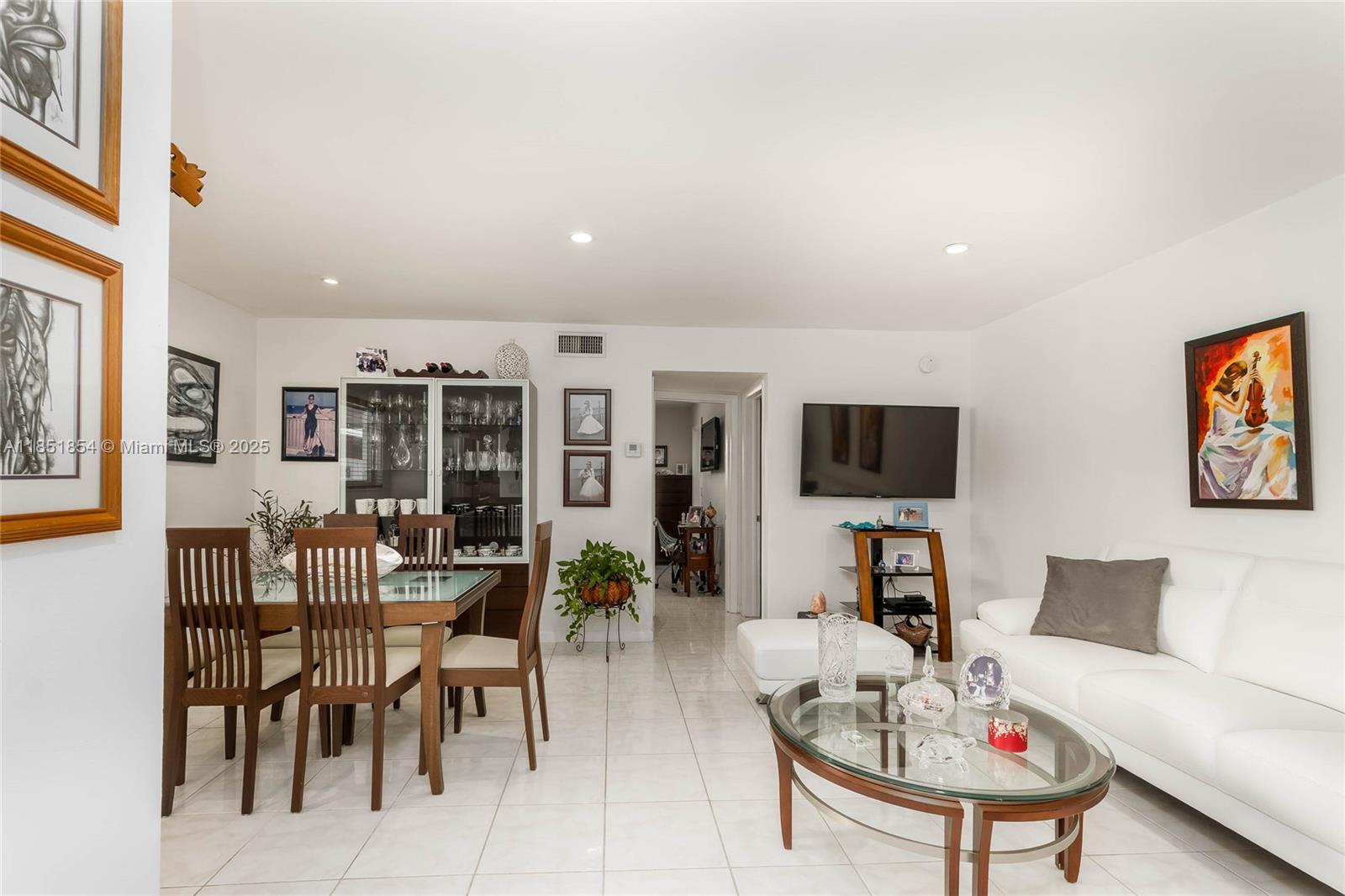 This living and dining area features white tile floors, a white sofa, and a glass-topped table — 581 Blue Heron Dr # B, Hallandale Beach FL 33009, HALLANDALE BEACH, FL