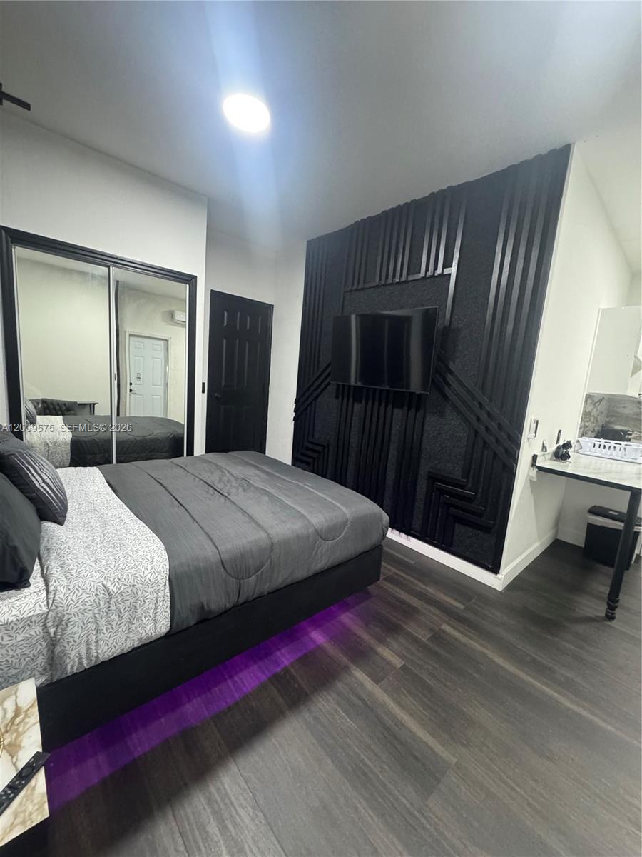 A bedroom features a bed with purple under-lighting, a black accent wall, and mirrored closet doors — 12959 SW 229th Ter # 0, Miami FL 33170, MIAMI, FL
