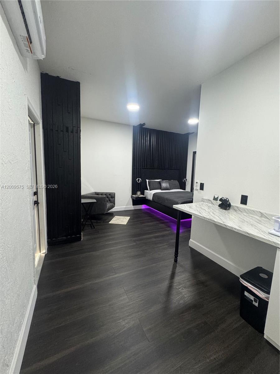 This bedroom features dark wood-look flooring, a black accent wall, and a marble-topped counter — 12959 SW 229th Ter # 0, Miami FL 33170, MIAMI, FL