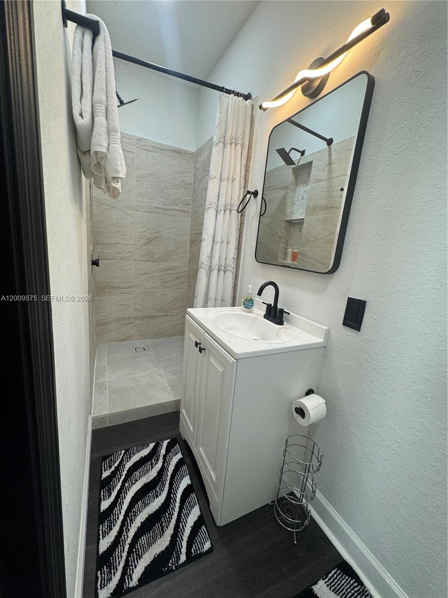A small bathroom features a walk-in shower, a white vanity, and a black-framed mirror — 12959 SW 229th Ter # 0, Miami FL 33170, MIAMI, FL