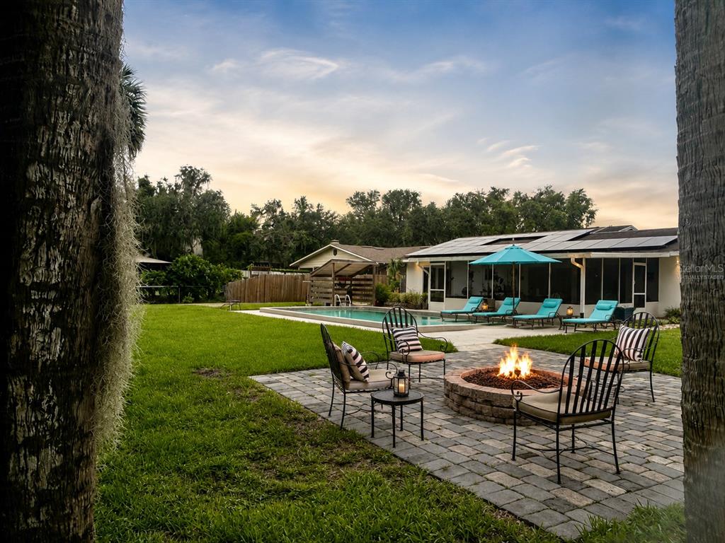 A backyard features a stone fire pit, patio furniture, a swimming pool, and a house — 2950 N SHELL ROAD, DELAND, FL