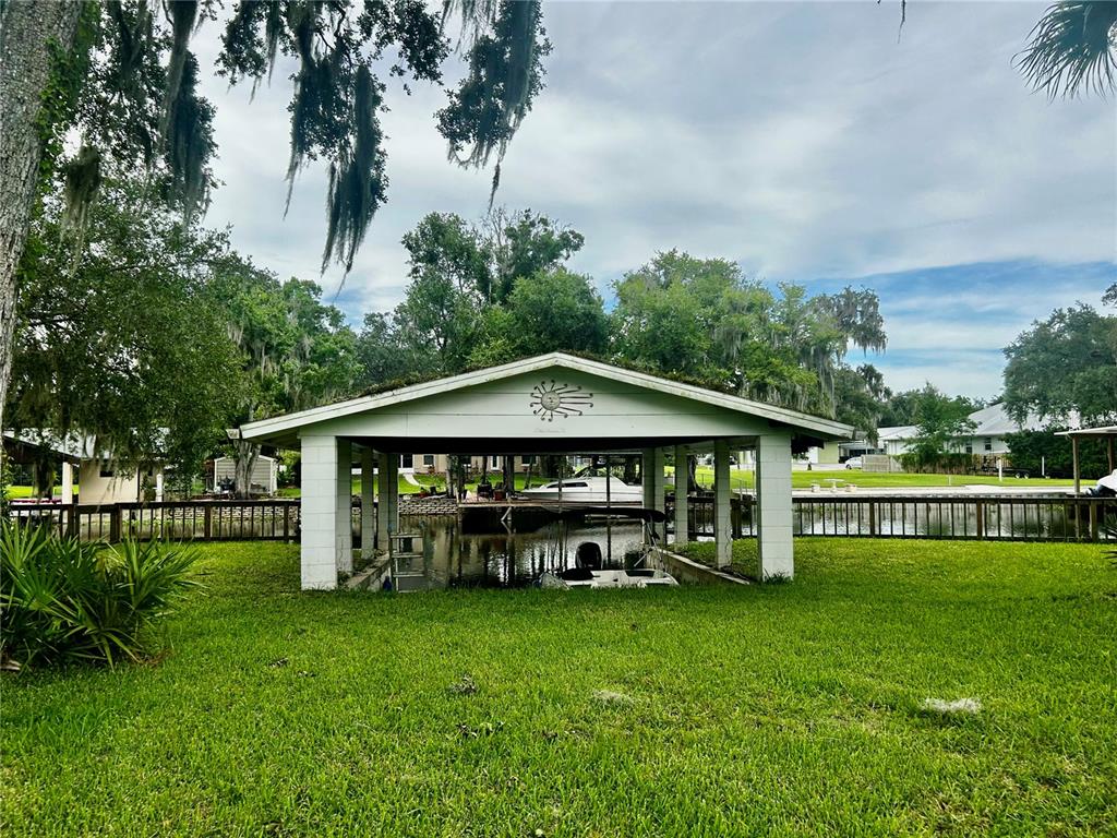 A boat slip with a covered roof sits on a grassy lawn by a canal — 2950 N SHELL ROAD, DELAND, FL