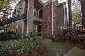A two-story apartment building exterior features tan siding, brick accents, and an outdoor metal staircase — 5136 PARK CENTRAL DRIVE UNIT 215, ORLANDO, FL