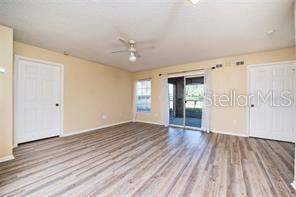 An empty room features light-colored walls, wood-look flooring, a ceiling fan, and sliding glass doors — 5136 PARK CENTRAL DRIVE UNIT 215, ORLANDO, FL