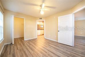 A bedroom with light-colored walls, wood-look flooring, a ceiling fan, and two white doors — 5136 PARK CENTRAL DRIVE UNIT 215, ORLANDO, FL