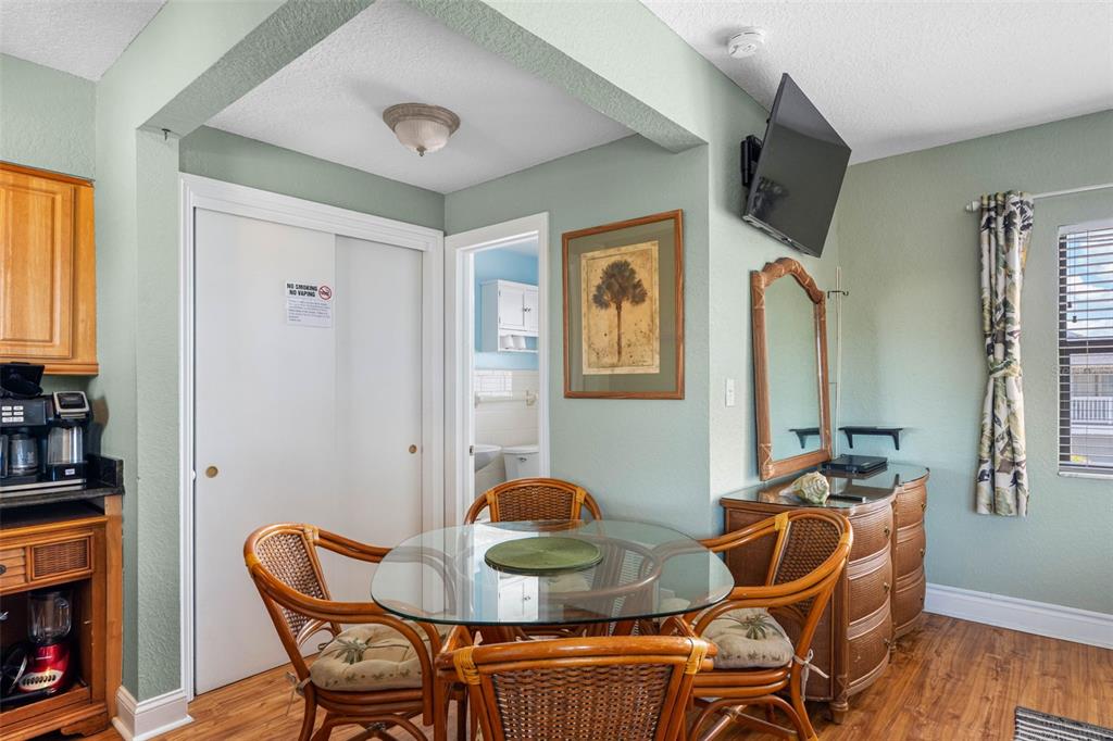 A dining area features a glass-topped wicker table, four chairs, a dresser, and a television — 16333 GULF BOULEVARD UNIT 210, ST PETERSBURG, FL