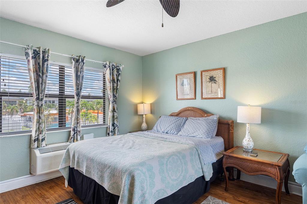 A bedroom with a bed, two nightstands, and a window overlooking a parking lot — 16333 GULF BOULEVARD UNIT 210, ST PETERSBURG, FL