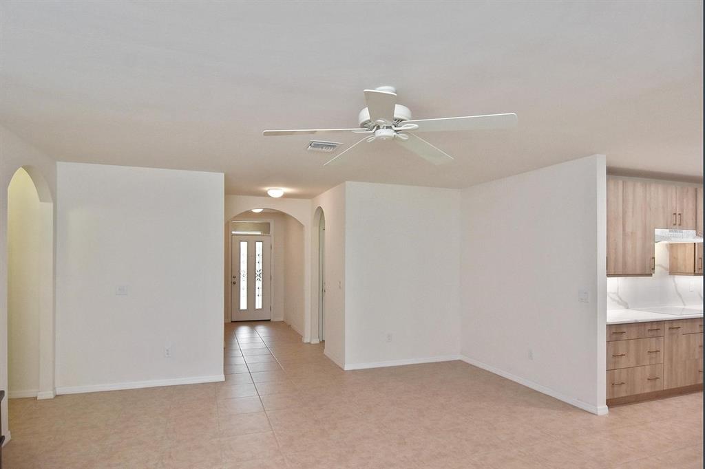 An open-concept living area features tile flooring, a ceiling fan, and an adjacent kitchen — 7132 MIKASA DRIVE, PUNTA GORDA, FL