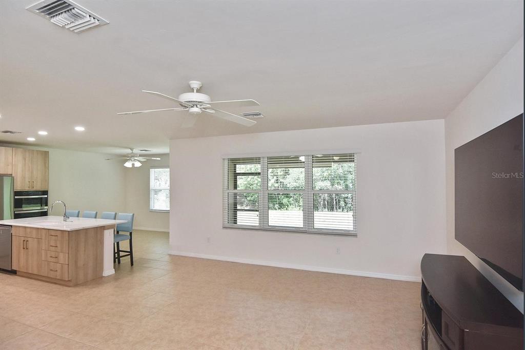 A living room with tile flooring and a ceiling fan opens to a kitchen area — 7132 MIKASA DRIVE, PUNTA GORDA, FL