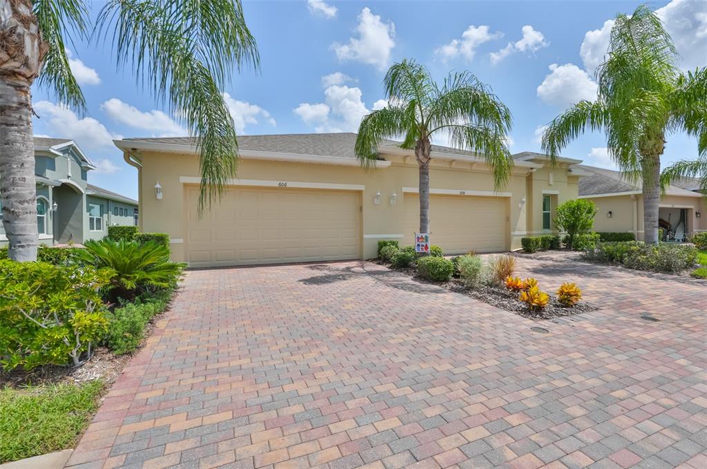 A beige house with two garage doors and a paved driveway under a blue sky — 606 CHIPPER DRIVE, SUN CITY CENTER, FL