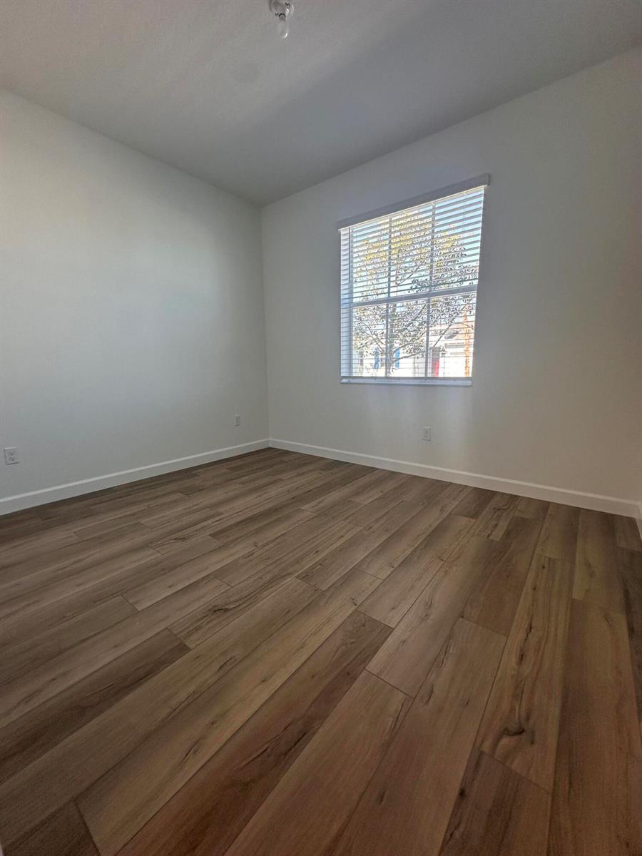 An empty bedroom features white walls, light-colored wood-look flooring, and a single window with blinds — 13776 Hero Path, Delray Beach FL 33484, DELRAY BEACH, FL