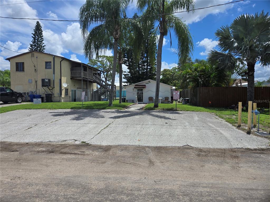 A small white building sits behind a cracked concrete parking lot with palm trees — 110 W SHELL POINT ROAD, RUSKIN, FL