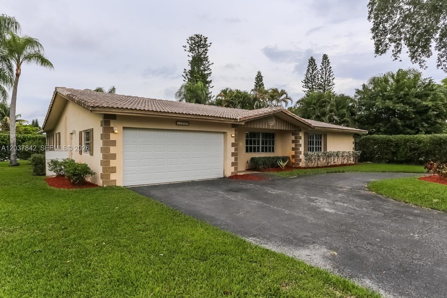 A single-story house with a two-car garage, tile roof, and a paved driveway — CORAL SPRINGS, FL