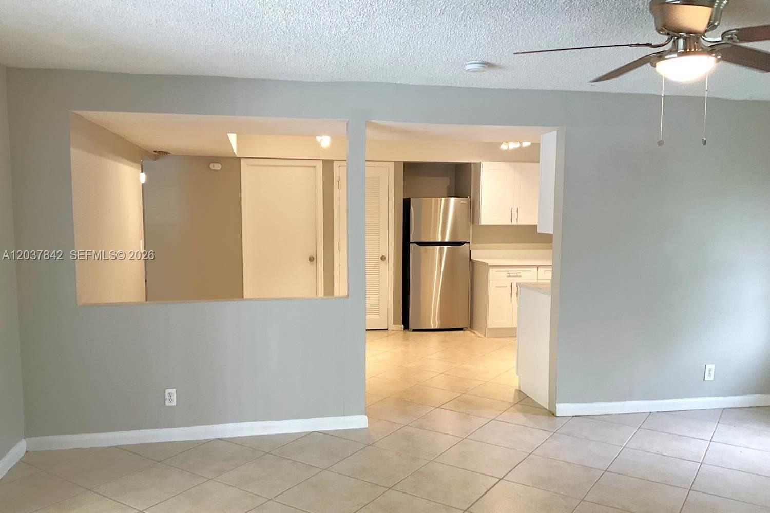 A view of a kitchen with stainless steel appliances and tile flooring from a living area — CORAL SPRINGS, FL