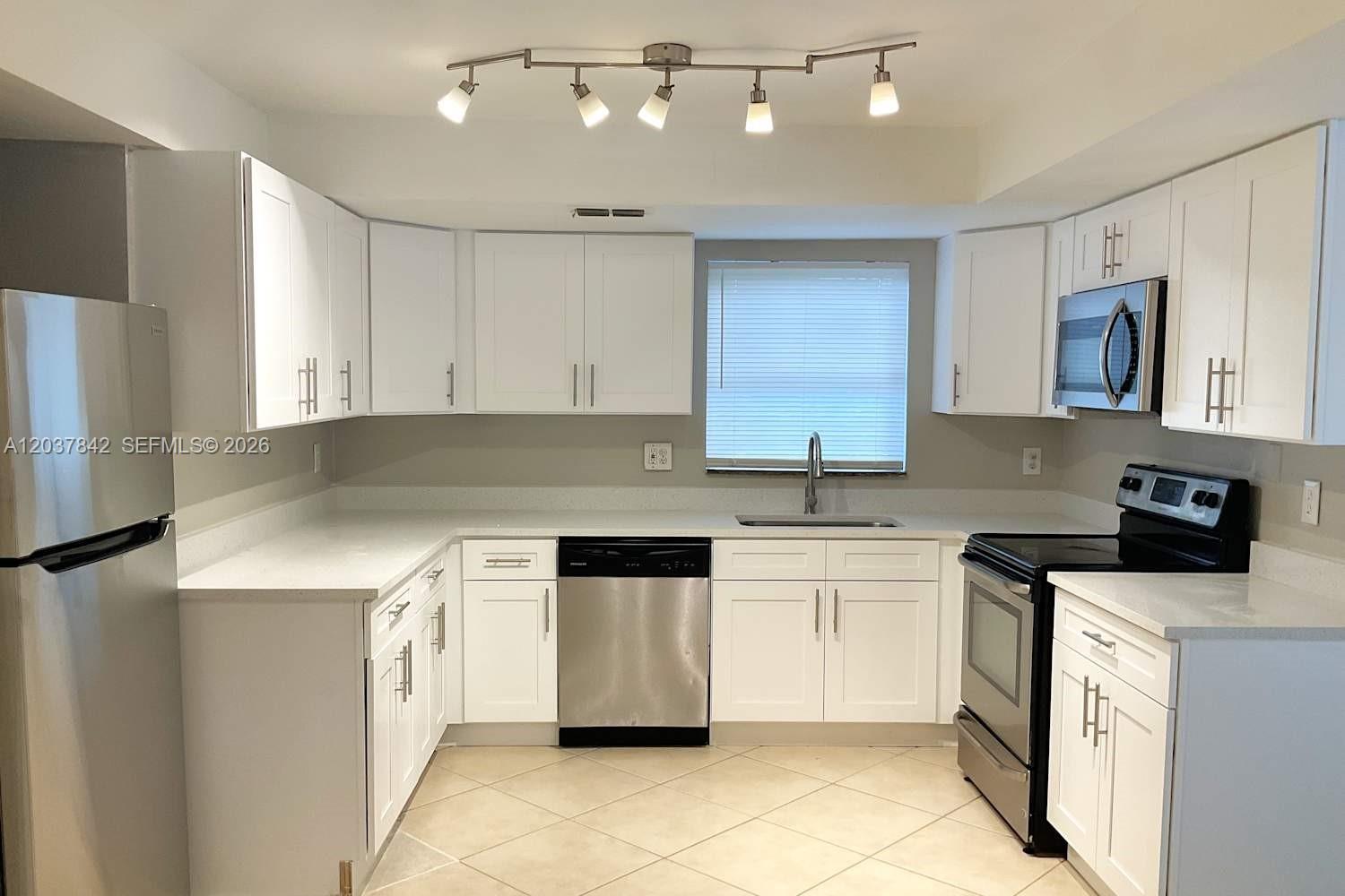 A kitchen features white cabinets, stainless steel appliances, and light-colored countertops — CORAL SPRINGS, FL