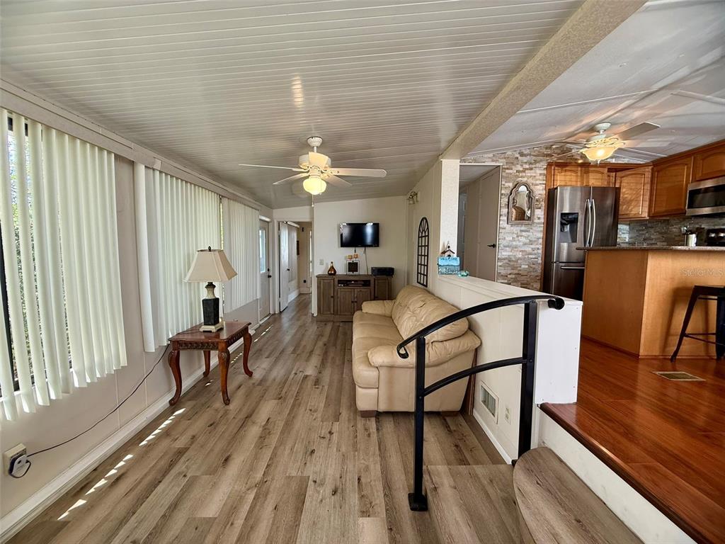 A living room with wood-look flooring, a beige sofa, and an adjacent kitchen area — 205 PANSY STREET, DAVENPORT, FL