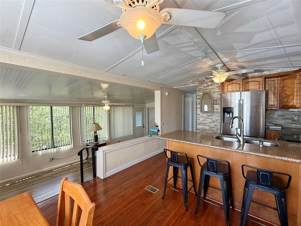 A kitchen with a granite island and bar stools overlooks a living area with windows — 205 PANSY STREET, DAVENPORT, FL