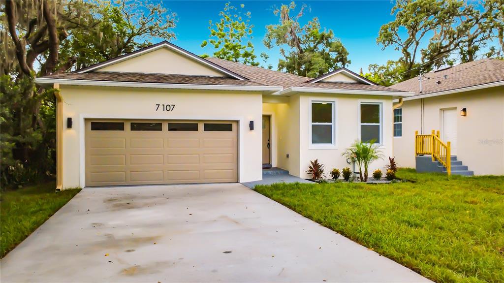 A single-story house with a beige garage, light-colored stucco exterior, and a concrete driveway — 7107 BLEDSOE AVENUE, ORLANDO, FL