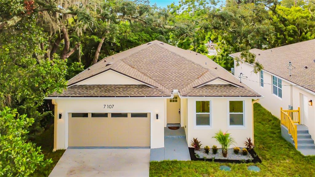 An exterior view of a single-story house with a tan garage and a light-colored facade — 7107 BLEDSOE AVENUE, ORLANDO, FL