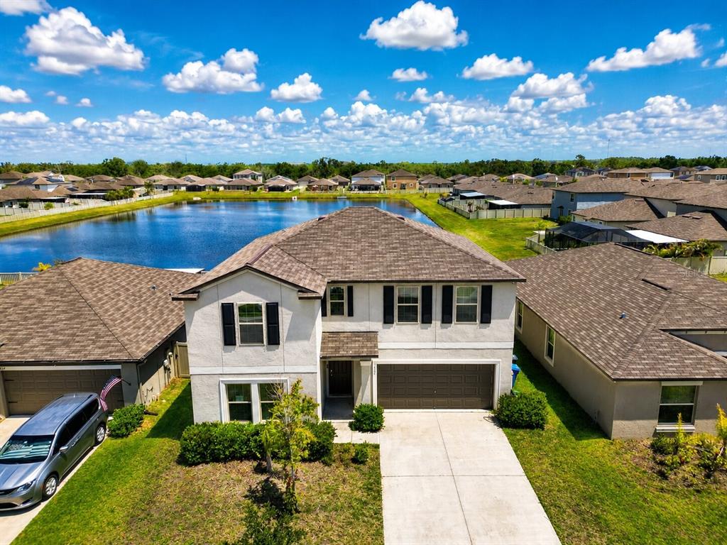 An aerial view of a two-story suburban house with a brown roof and pond — 5462 GRAYS HARBOR COURT, WIMAUMA, FL