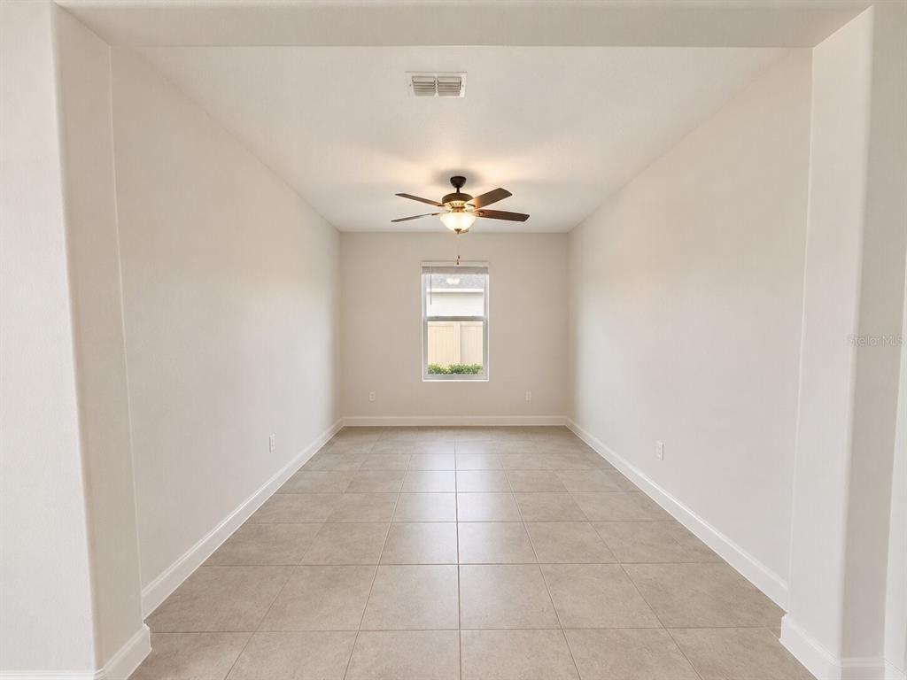 An empty room features light-colored tile flooring, white walls, and a ceiling fan — 5462 GRAYS HARBOR COURT, WIMAUMA, FL