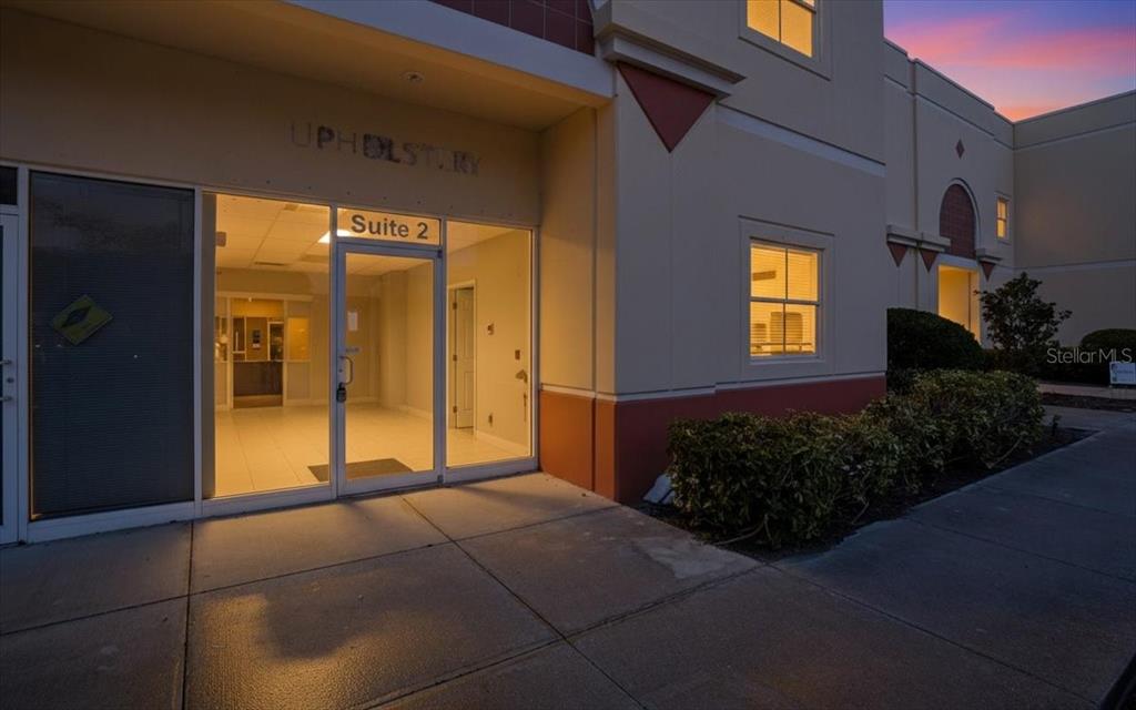 The exterior of a commercial building features a glass entrance door labeled Suite 2 — 6321 PORTER UNIT 2, SARASOTA, FL