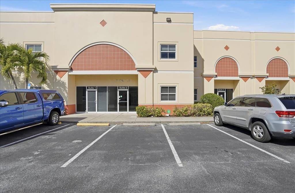The exterior of a commercial building features multiple suites with arched architectural details and parking — 6321 PORTER UNIT 2, SARASOTA, FL