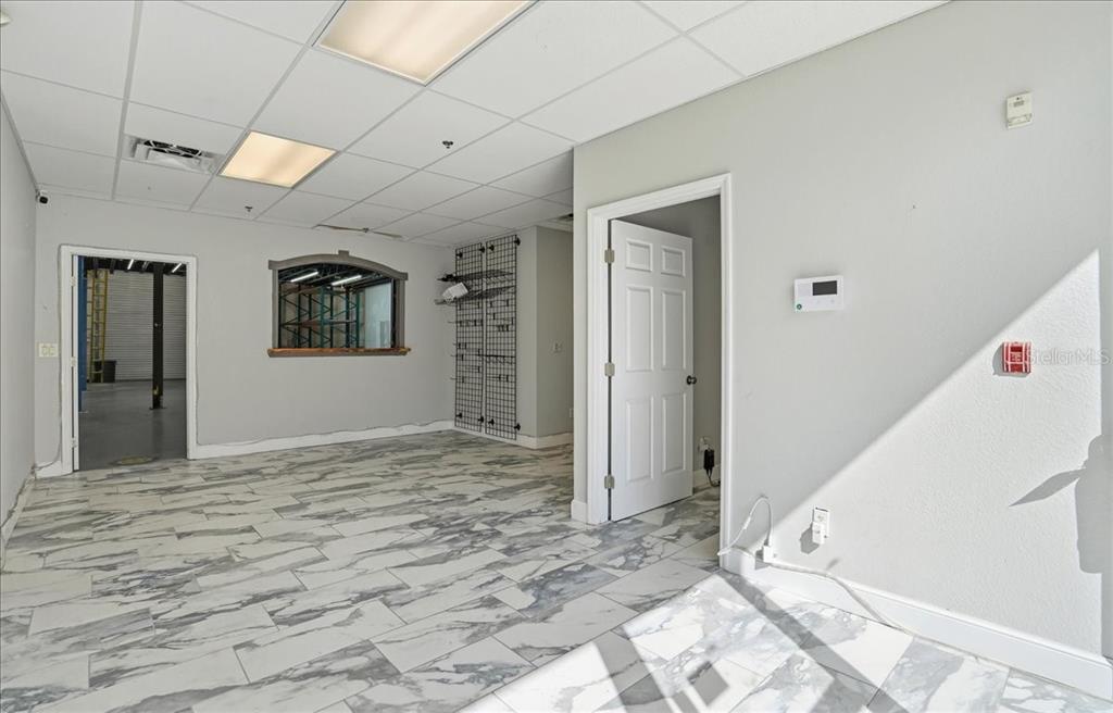 An office space features gray marble-look tile flooring, a drop ceiling, and a pass-through window — 6321 PORTER UNIT 2, SARASOTA, FL