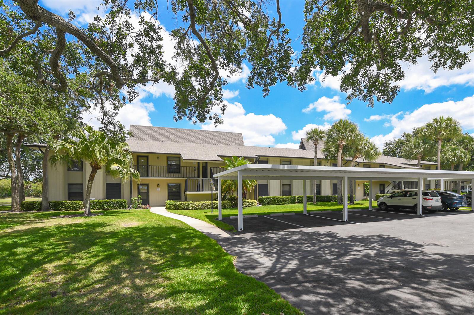 A two-story apartment building with a covered parking area and surrounding lawn and trees — 20 Plantation Drive # 101, Vero Beach FL 32966, VERO BEACH, FL