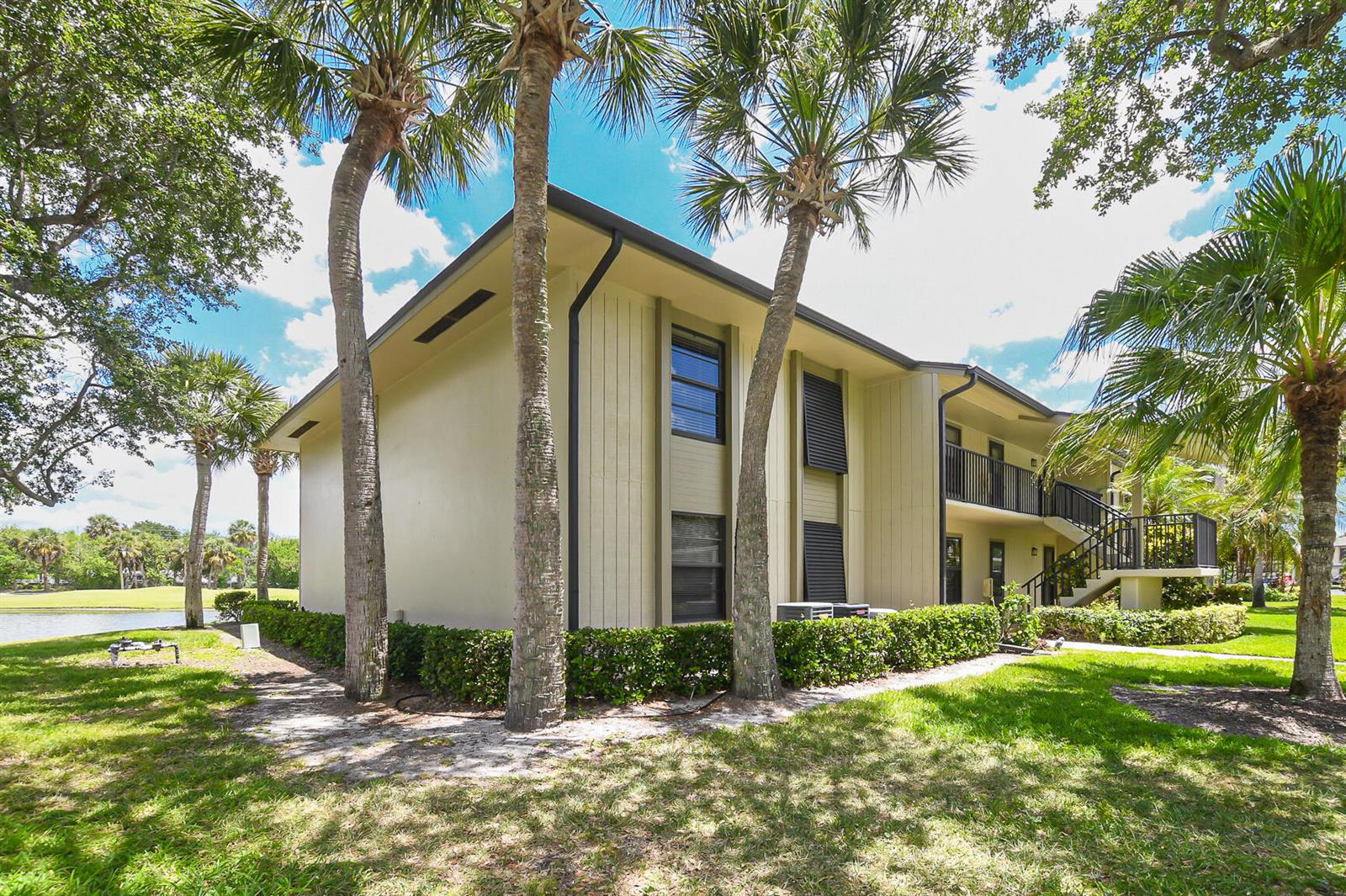 A two-story apartment building with beige siding, black shutters, and palm trees on a lawn — 20 Plantation Drive # 101, Vero Beach FL 32966, VERO BEACH, FL