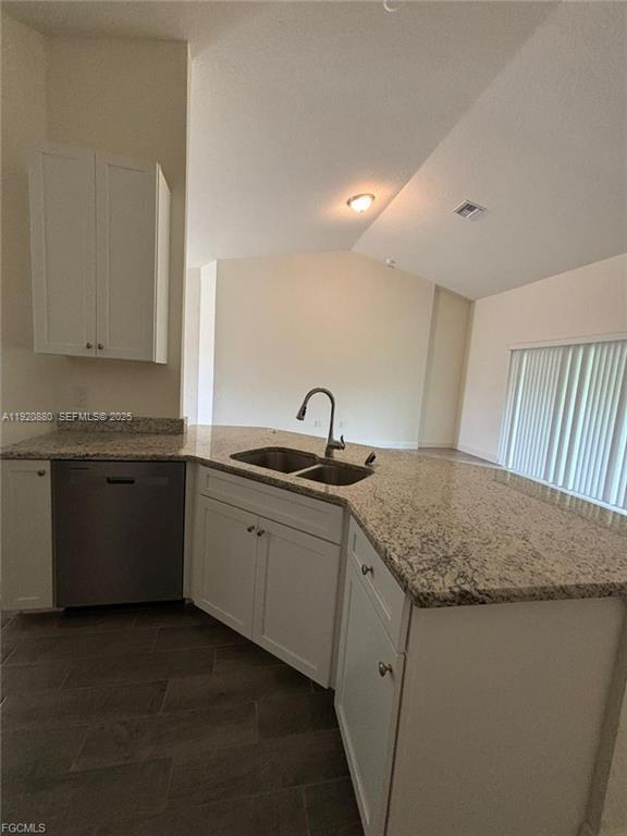 A kitchen features white cabinets, granite countertops, a stainless steel dishwasher, and tile flooring — 2614 27th ST W, Lehigh Acres FL 33971, LEHIGH ACRES, FL