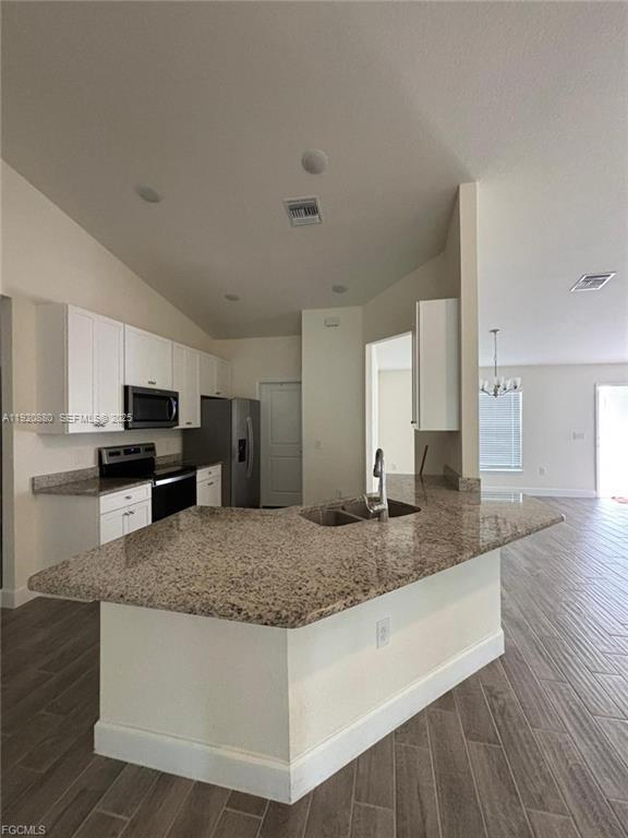 A kitchen features white cabinets, granite countertops, a central island with a sink, and tile flooring — 2614 27th ST W, Lehigh Acres FL 33971, LEHIGH ACRES, FL