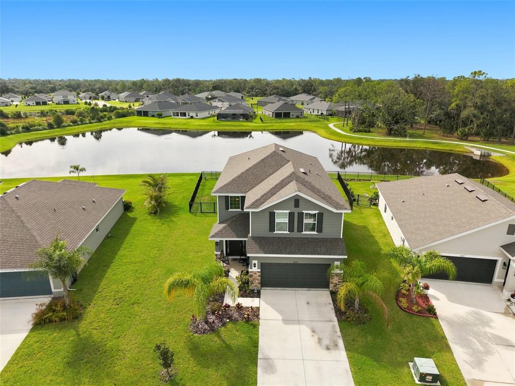 An aerial view of a two-story house with a garage, lawn, and backyard pond — 16331 66TH LANE E, PARRISH, FL