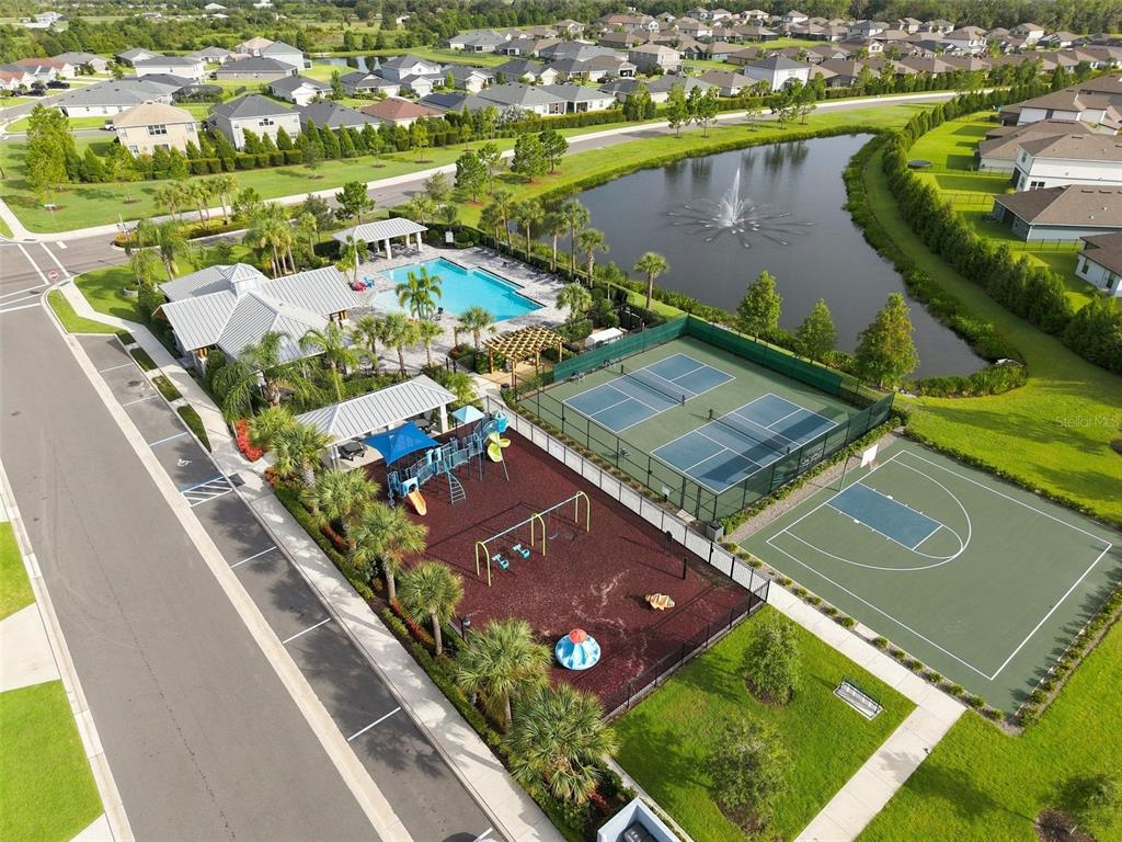 An aerial view shows a community pool, tennis courts, basketball court, and playground near a pond — 16331 66TH LANE E, PARRISH, FL