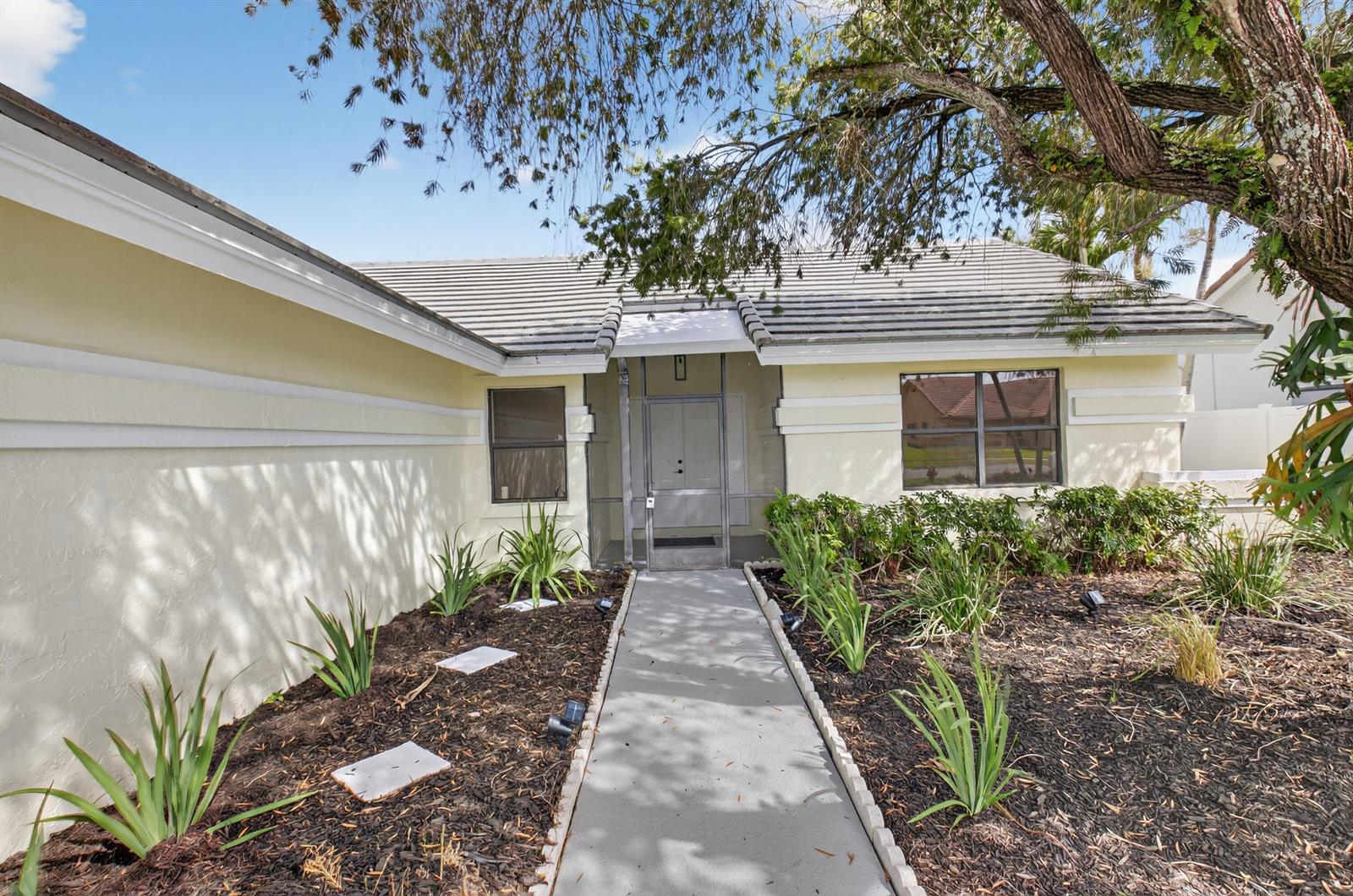 A light-colored house exterior features a concrete walkway leading to a screened front entryway — 9537 Majestic Way, Boynton Beach FL 33437, BOYNTON BEACH, FL