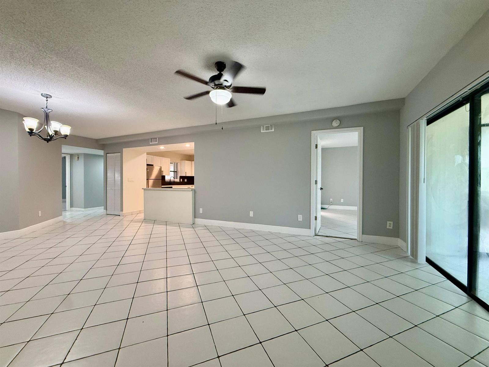 A spacious living area features white tiled floors, a ceiling fan, and an open kitchen — 9633 Riverside Drive # E2, Coral Springs FL 33071, CORAL SPRINGS, FL
