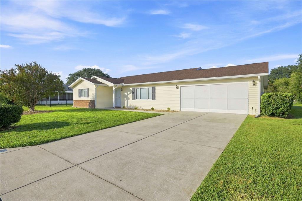 A single-story house with light yellow siding, a brown roof, and a concrete driveway — 17960 SE 108TH COURT, SUMMERFIELD, FL